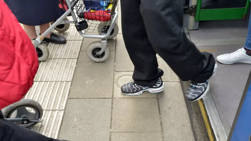 Beine und Füße mehrerer Menschen, die aus der Straßenbahn aussteigen.