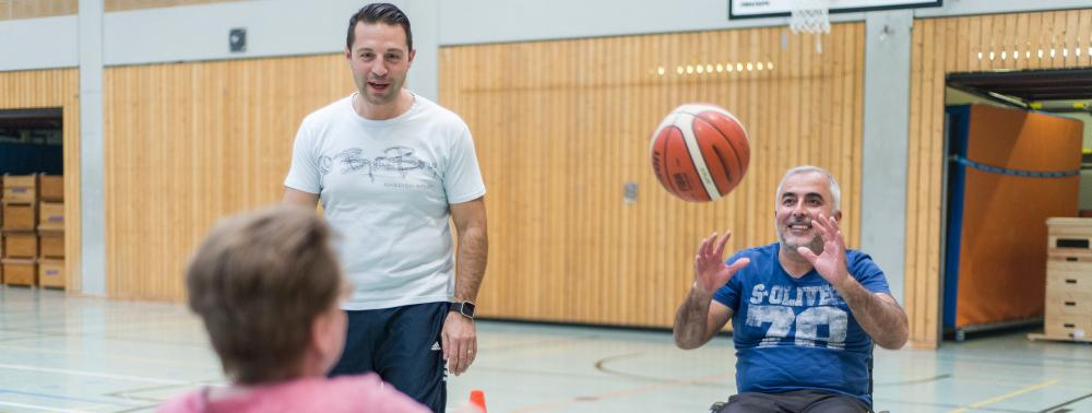 Eine Frau und ein Mann spielen Rollstuhlbasketball