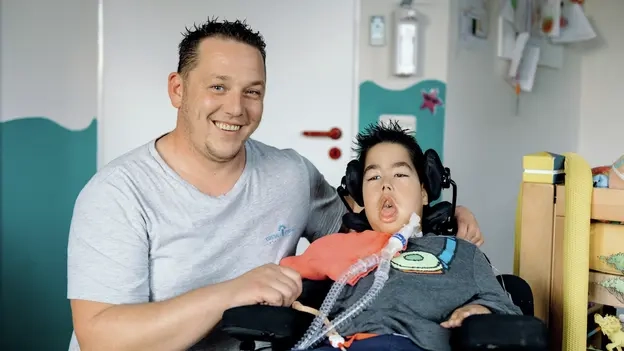 Simon liegt im Rollstuhl, links neben ihm ist sein Betreuer Andi.