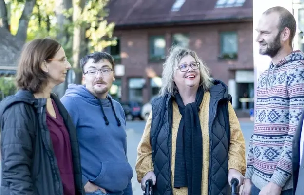 Eine Gruppe von Menschen mit und ohne Behinderung an einer Bürgerbus-Haltestelle