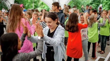 Mehrere Kinder in Zweiergruppen. Jede Zweiergruppe klatscht sich ab.