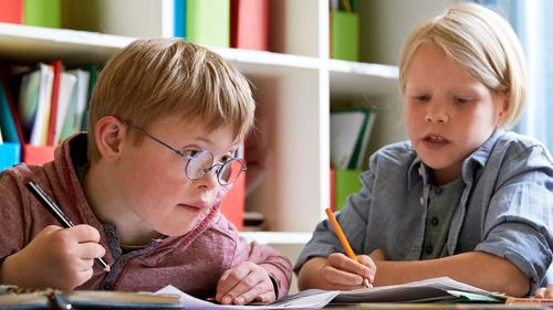 Zwei Kinder mit Stiften in der Hand vor einem Regal.