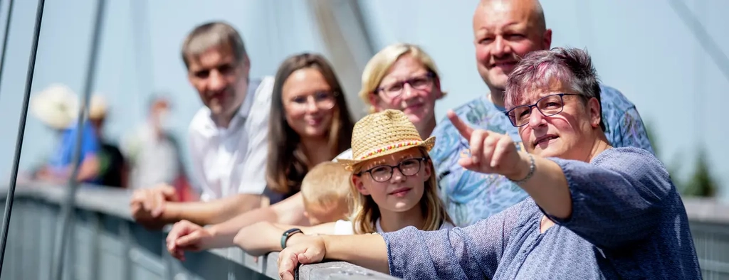 Eine Gruppe von Menschen steht auf dem Skywalk. Sie stehen am Geländer und schauen in die Ferne.