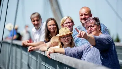 Eine Gruppe von Menschen steht auf dem Skywalk. Sie stehen am Geländer und schauen in die Ferne.