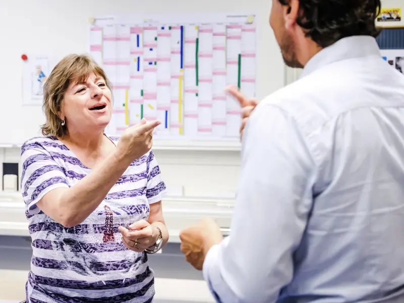 Eine Frau und ein Mann gebärden vor einem Whiteboard