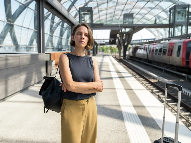 Ein Potraitbild von Kassandra Wedel. Sie steht an einem Bahnsteig und hält die Arme verschränkt vor dem Körper.