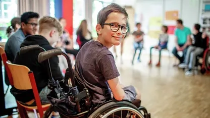 Ein Junge im Rollstuhl sitzt mit anderen Kindern in einem Stuhlkreis.