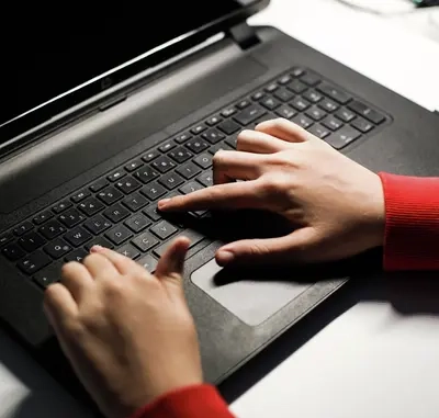 Eine Laptop-Tastatur, darauf zwei Hände.