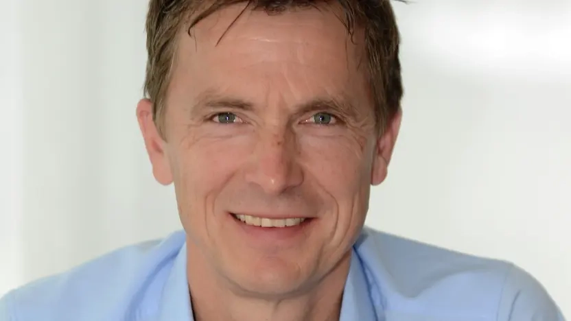 Porträt von Volker Anneken, ein Mann im mittleren Alter mit blauem Hemd und blonden Haaren