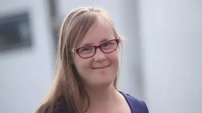 Porträt von Carina Kühne: eine junge Frau mit langen blonden Haaren und Brille.