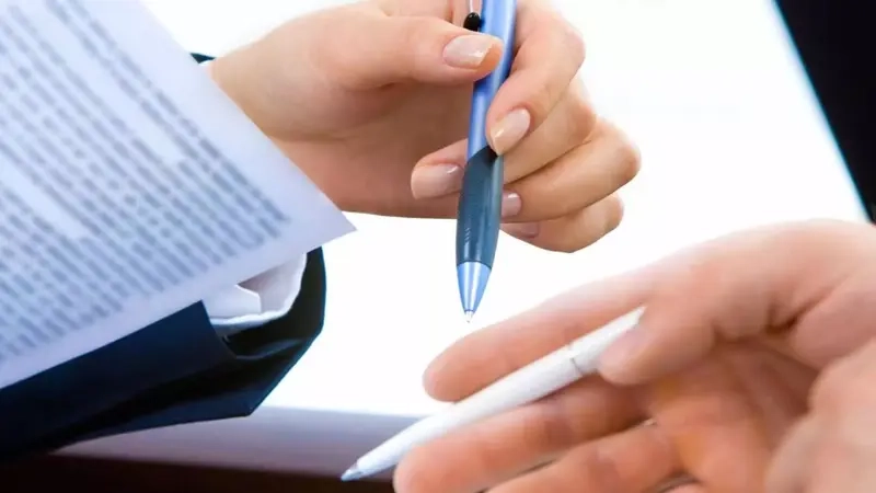 Die Hände von zwei Personen halten Stifte und Unterlagen.