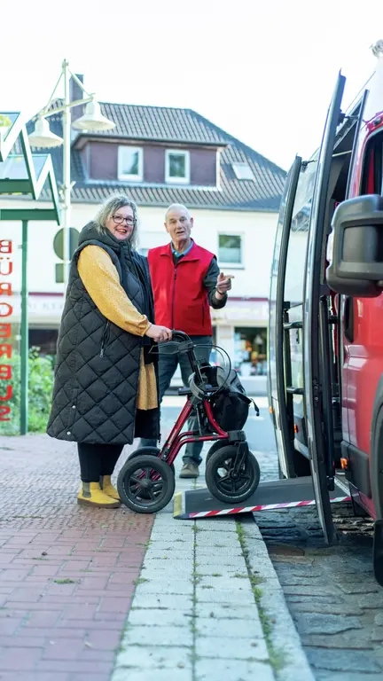 Eine Frau mit Rollator geht über eine Rampe in einen Bus