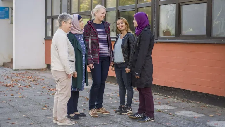 Fünf Frauen unterschiedlichen Alters unterhalten sich, zwei tragen ein Kopftuch.