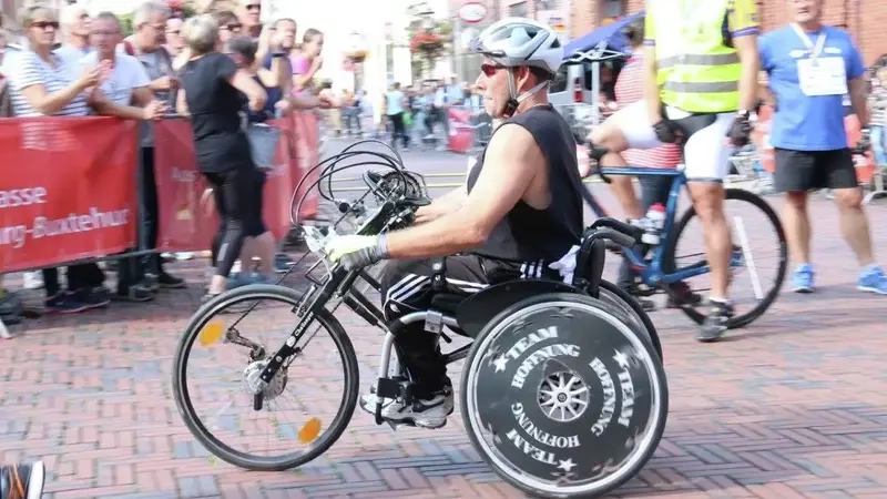 Handbiker mit Helm und dunklem, kurzärmeligen Sportdress auf der Strecke beim Hamburg-Marathon