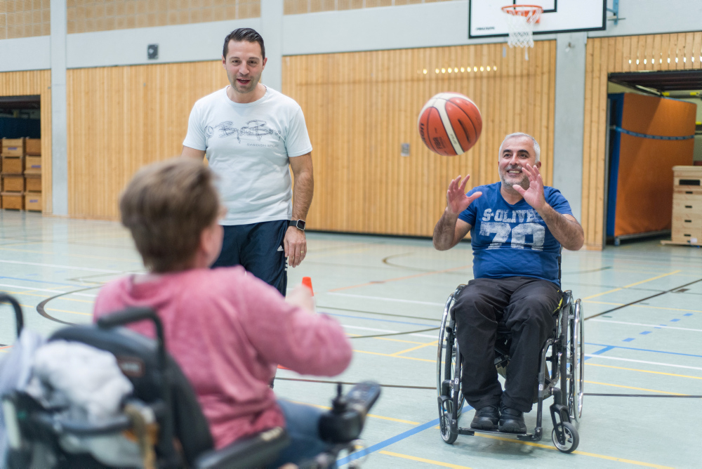 Eine Frau und ein Mann spielen Rollstuhlbasketball
