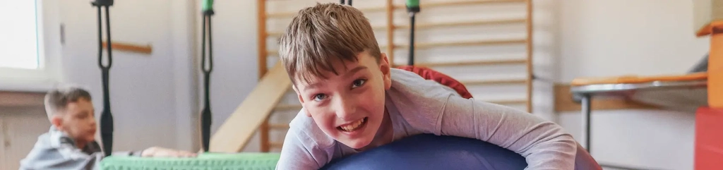 Ein Junge spielt mit einem blauem Gymnastikball.