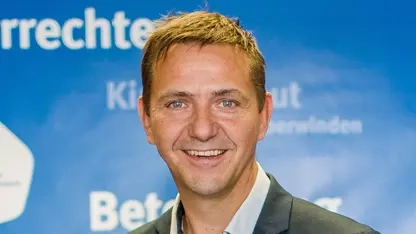 Porträt von Holger Hofmann, ein Mann im mittleren Alter im Anzug mit blonden Haaren