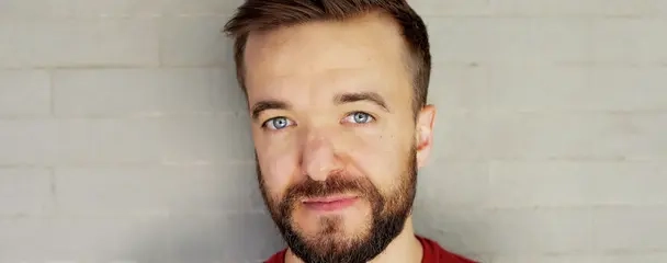 Ein Porträtfoto des Leichtathleten und Paralympioniken Mathias Mester. Er trägt einen roten Pullover und lächelt in die Kamera.