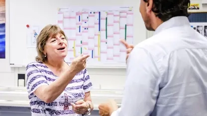 Eine Frau und ein Mann gebärden vor einem Whiteboard