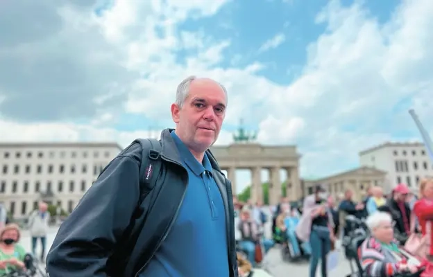 Ottmar Miles-Paul - ein Mann mit kurzen, grauen Haaren - steht vor dem Brandenburger Tor. Im Hintergrund sieht man unscharf weitere Menschen.