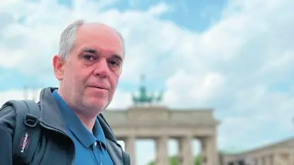 Ottmar Miles-Paul - ein Mann mit kurzen, grauen Haaren - steht vor dem Brandenburger Tor. Im Hintergrund sieht man unscharf weitere Menschen.