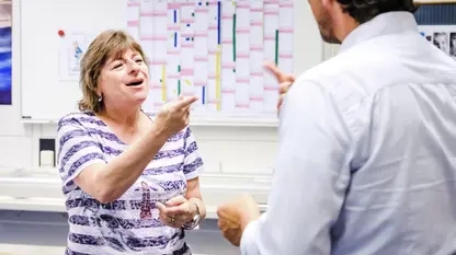 Eine Frau und ein Mann gebärden vor einem Whiteboard