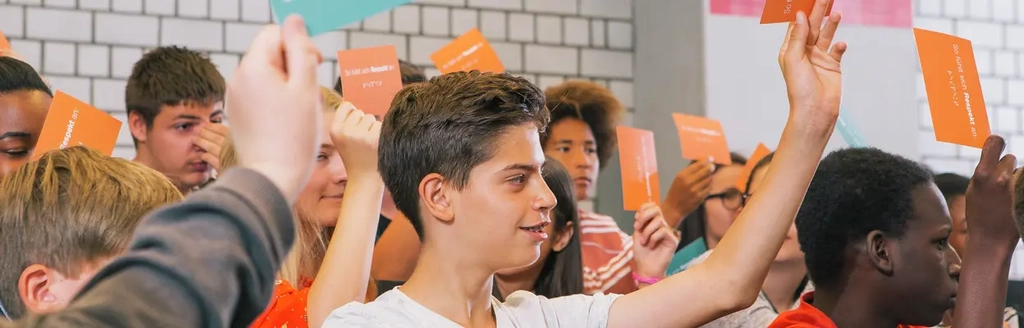 Schüler*innen melden sich mit bunten Postkarten in den Händen.