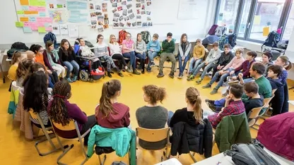 Etwa 30 Jugendliche sitzen im Stuhlkreis mit einem Erwachsenen zusammen.