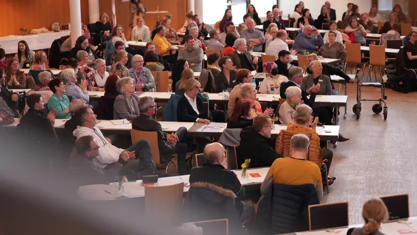 Ein großer Saal mit vielen Menschen, die an Tischen sitzen