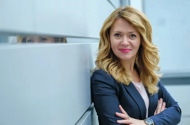 Olga Nevska, eine Frau mit langen blonden Haaren und pinkem Lippenstift.