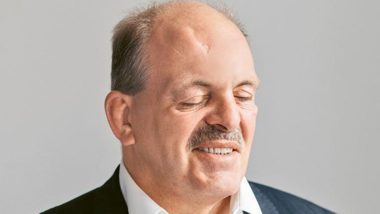 Lächelnder Mann mit Schnauzbart, die Augen sind geschlossen. 