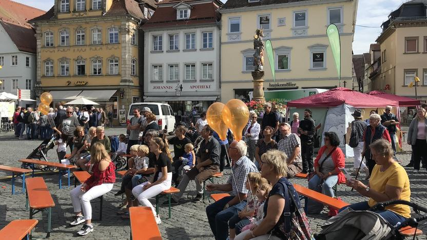 Zuschauer sitzen auf Bierbänken auf dem Marktplatz von Schwäbisch Gmünd